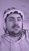 a selfie of a white person, wearing either headphones or a helmet, making an odd expression. the photo is edited to be colorized into a monochrome purple-ish color palette.