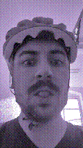 a selfie of a white person, wearing either headphones or a helmet, making an odd expression. the photo is edited to be colorized into a monochrome purple-ish color palette.