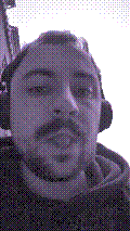 a selfie of a white person, wearing either headphones or a helmet, making an odd expression. the photo is edited to be colorized into a monochrome purple-ish color palette.