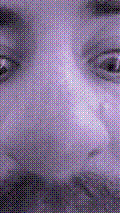 a selfie of a white person, wearing either headphones or a helmet, making an odd expression. the photo is edited to be colorized into a monochrome purple-ish color palette.
