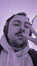 a selfie of a white person, wearing either headphones or a helmet, making an odd expression. the photo is edited to be colorized into a monochrome purple-ish color palette.