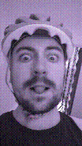a selfie of a white person, wearing either headphones or a helmet, making an odd expression. the photo is edited to be colorized into a monochrome purple-ish color palette.