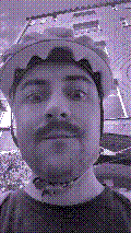 a selfie of a white person, wearing either headphones or a helmet, making an odd expression. the photo is edited to be colorized into a monochrome purple-ish color palette.