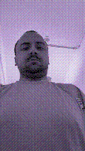 a selfie of a white person, wearing either headphones or a helmet, making an odd expression. the photo is edited to be colorized into a monochrome purple-ish color palette.