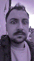 a selfie of a white person, wearing either headphones or a helmet, making an odd expression. the photo is edited to be colorized into a monochrome purple-ish color palette.