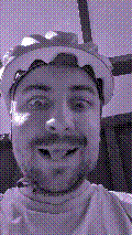 a selfie of a white person, wearing either headphones or a helmet, making an odd expression. the photo is edited to be colorized into a monochrome purple-ish color palette.