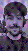 a selfie of a white person, wearing either headphones or a helmet, making an odd expression. the photo is edited to be colorized into a monochrome purple-ish color palette.