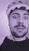 a selfie of a white person, wearing either headphones or a helmet, making an odd expression. the photo is edited to be colorized into a monochrome purple-ish color palette.